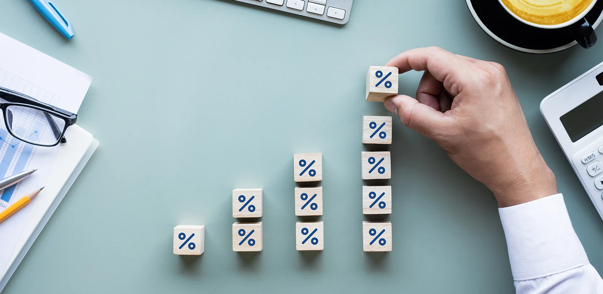 A hand stacking wooden blocks with percentage signs on them.