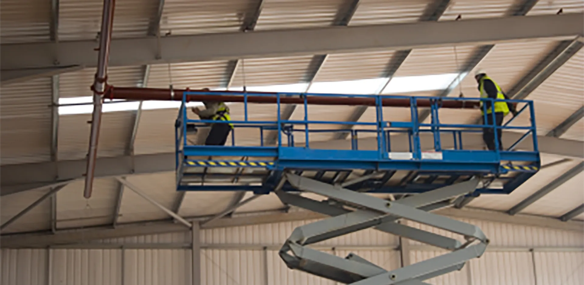 A pair of construction workers on a scissor lift.