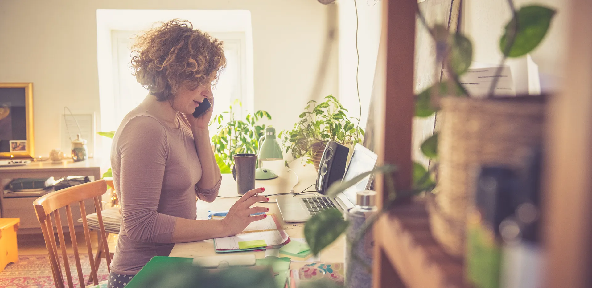 A woman speaking on the phone while working from home.