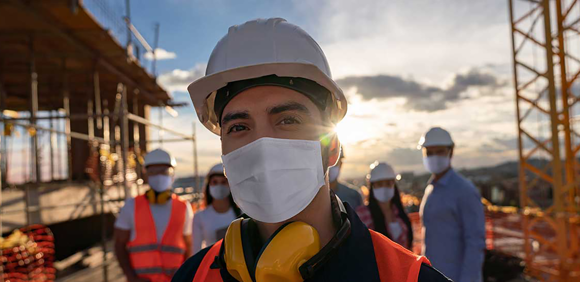 A group of construction professionals wearing safety gear and face masks.