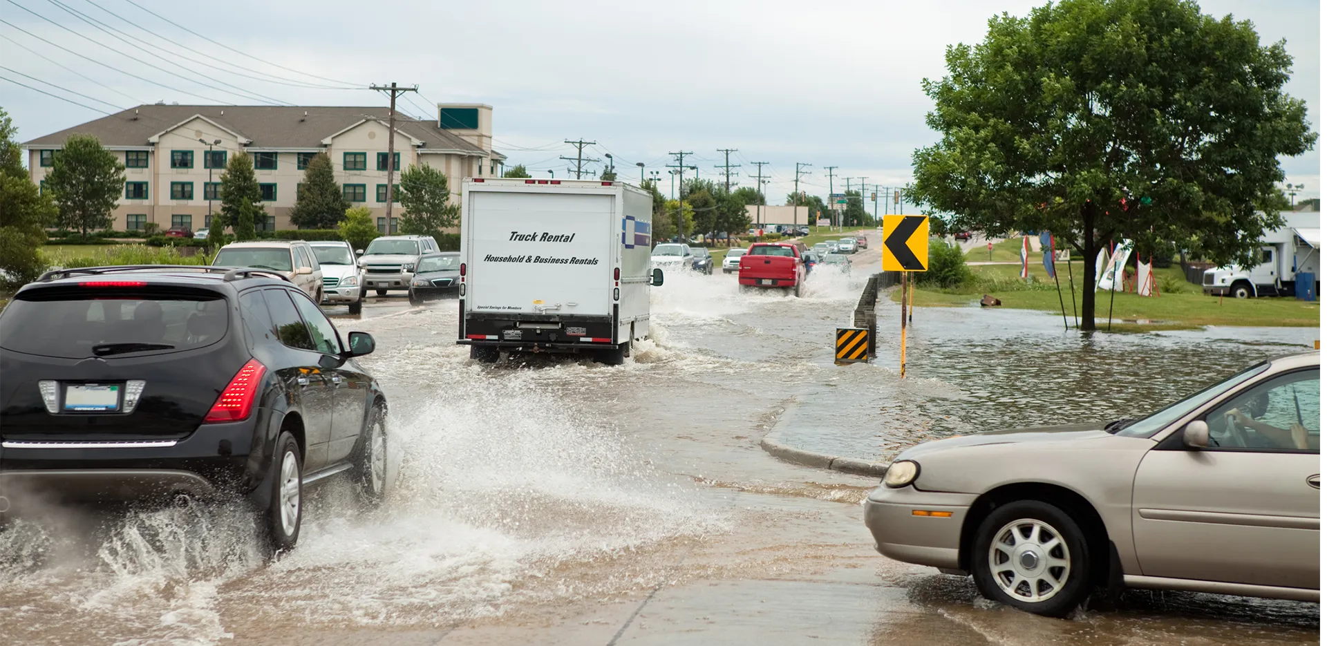 Cars driving along a flooded roadway.