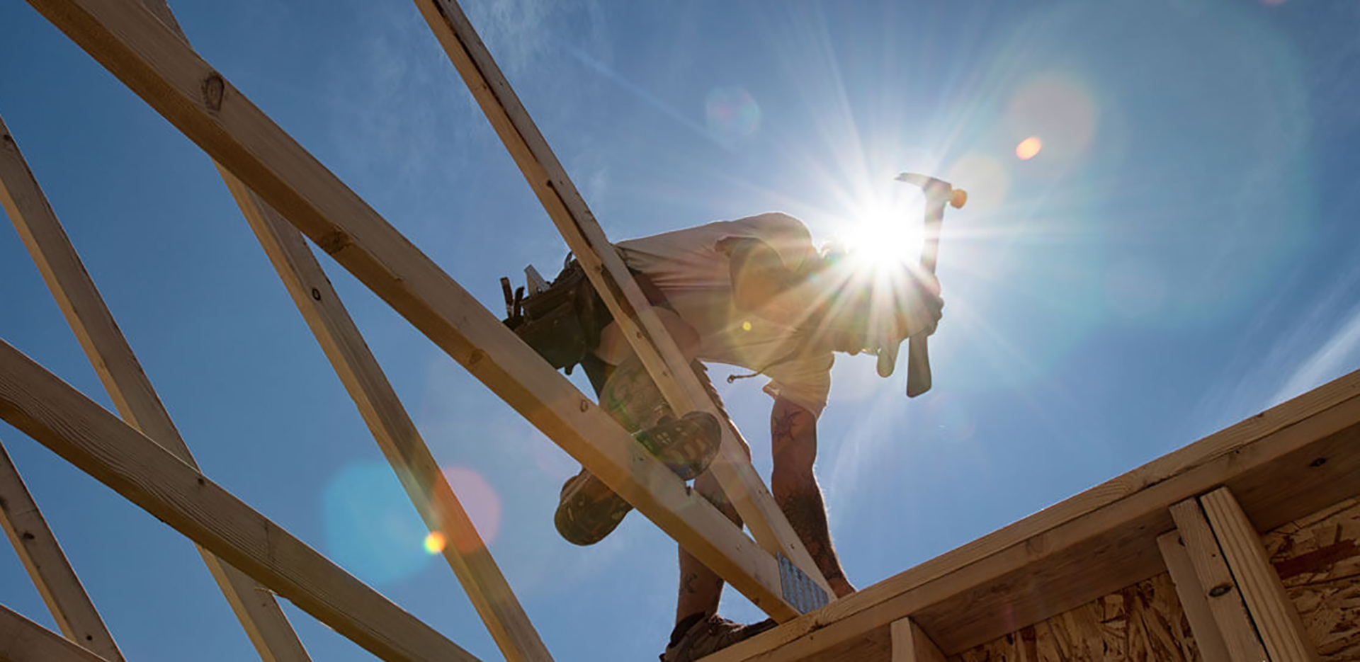 A construction worker working on the wooden frame of a house.