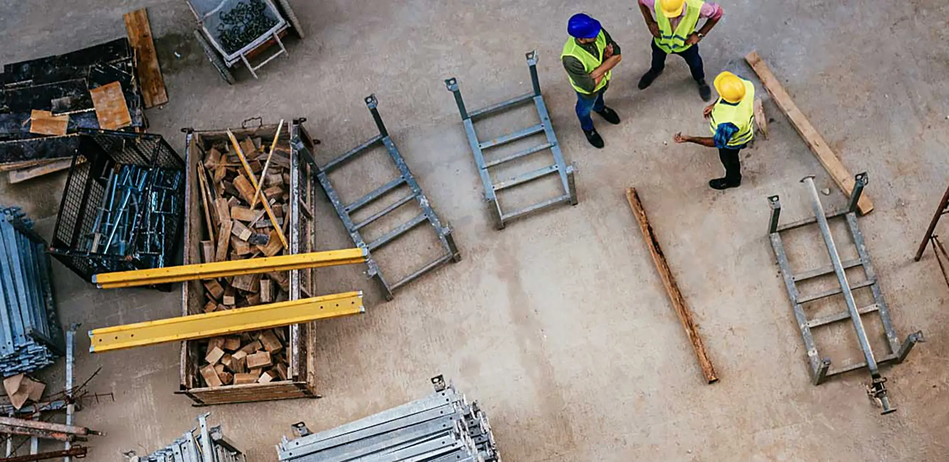 Construction workers standing next to tools and pieces of metal.