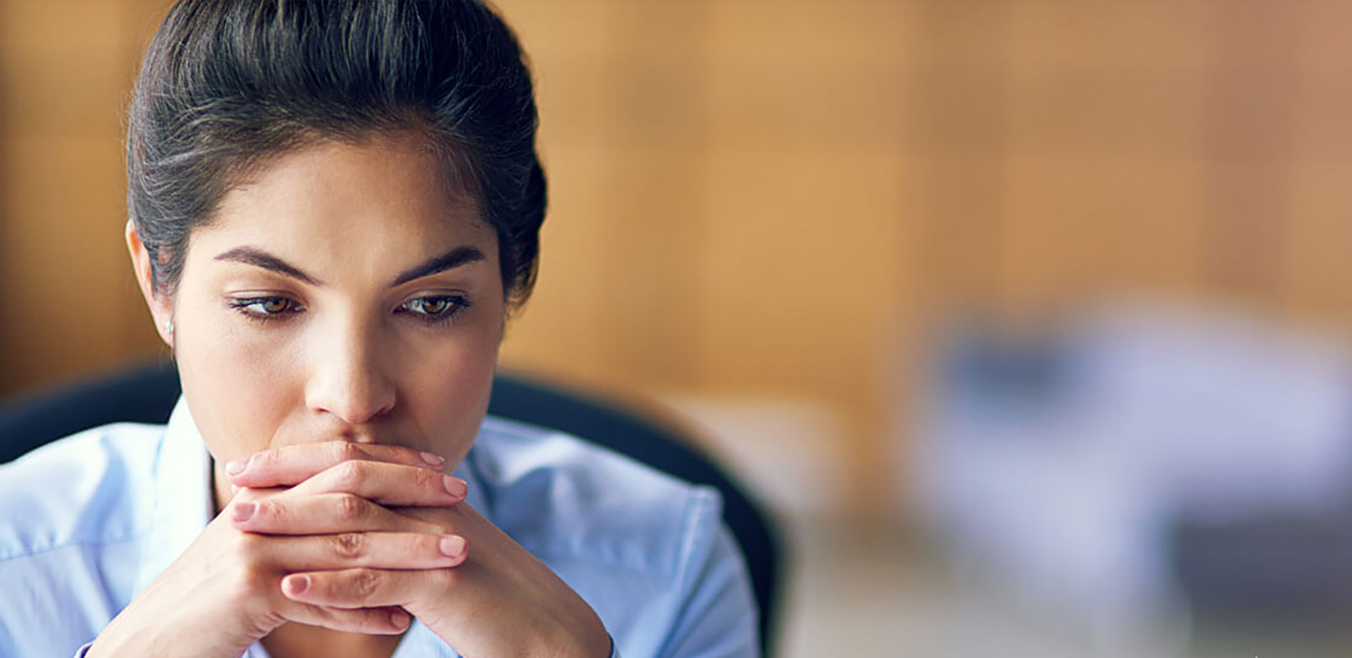 A professional sitting with their hands folded looking pensive.