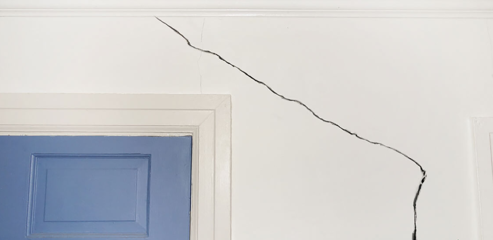 A large crack above a door in a home.