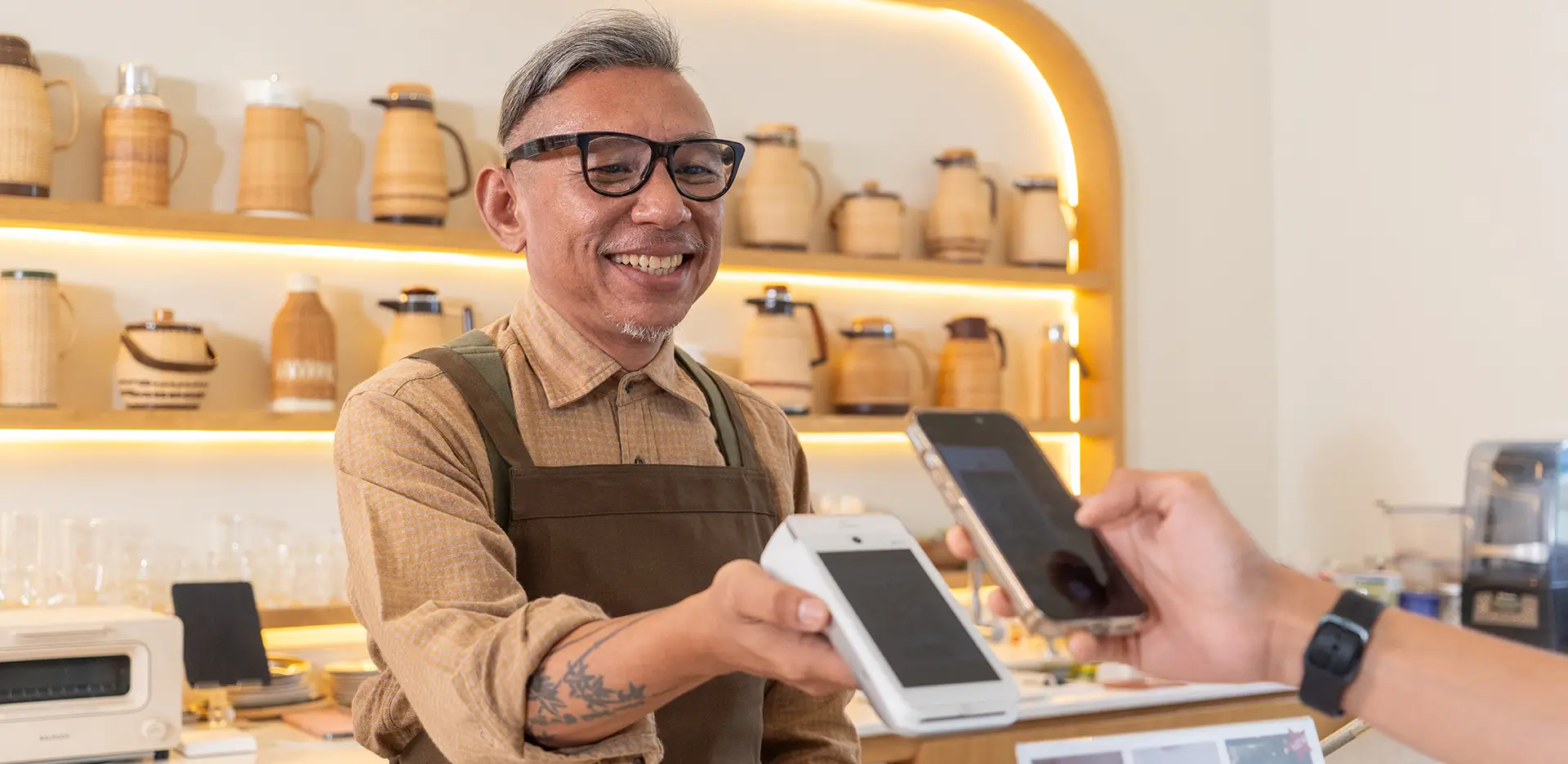 A business owner holding out a payment device for someone to pay with their phone.