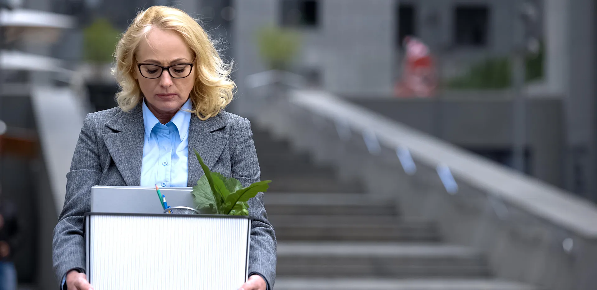 A professional holding a box with supplies from her desk.