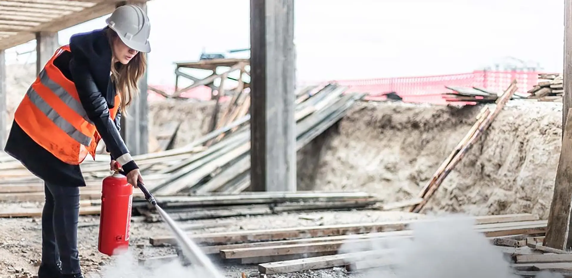 A person wearing an orange vest using a fire hydrant on a construction site.