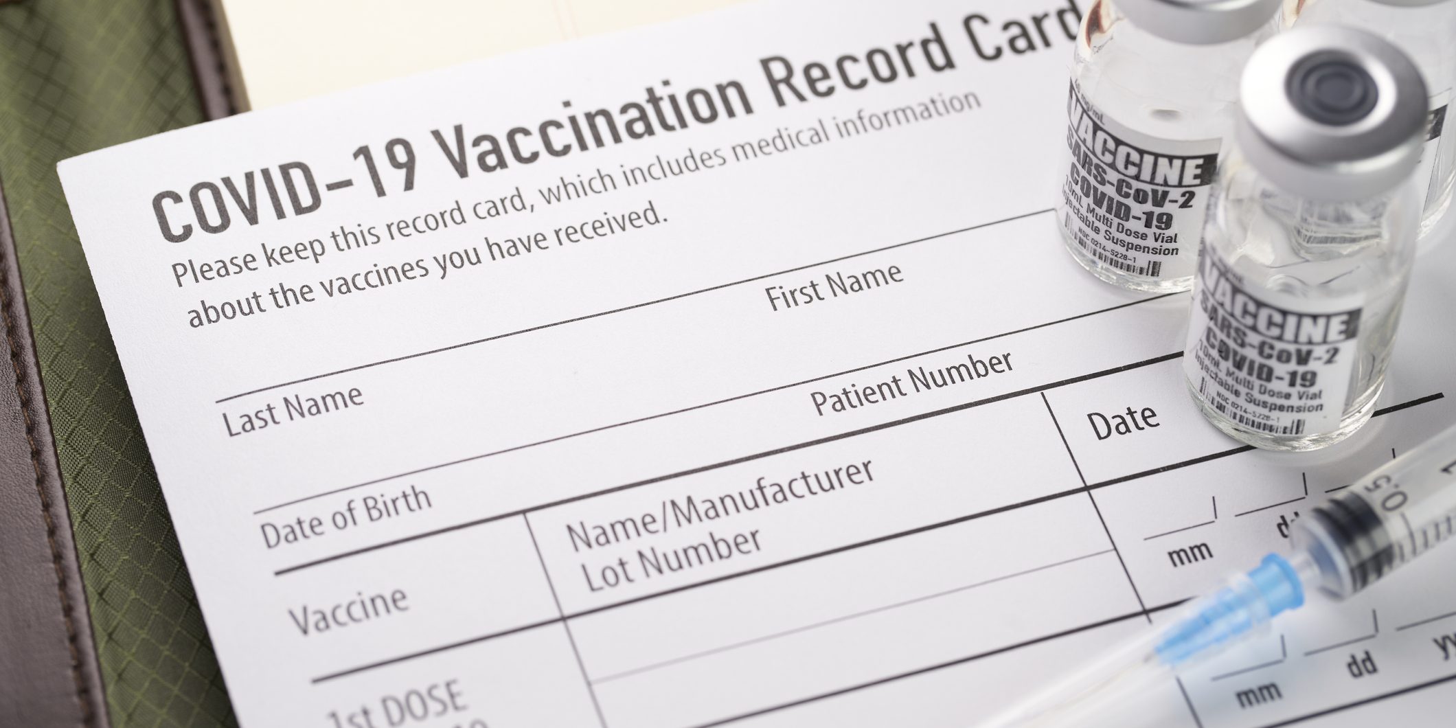 Covid-19 vaccination record card with vials and syringe.