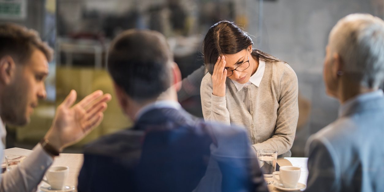 Young woman feeling disappointed after failing on a job interview in the office. The view is through glass.