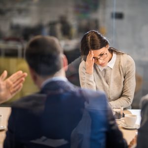 Young woman feeling disappointed after failing on a job interview in the office. The view is through glass.