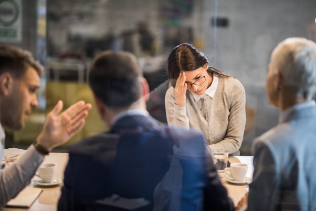 Young woman feeling disappointed after failing on a job interview in the office. The view is through glass.